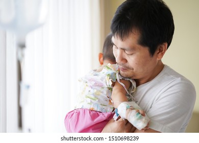 Asian Father Is Hugging And Holding His Baby To Relax With Love While The Child Admit As Inpatient In The Hospital, Concept Of Parent Take Care To Their Sickness Child In Family Lifestyle.