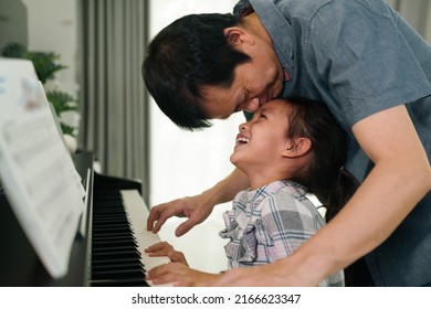 Asian father kissing daughter and smiling together with happy moment while playing piano at home,concept of love, bonding, relation, education, music, skill, mental health, parent and child in family  - Shutterstock ID 2166623347