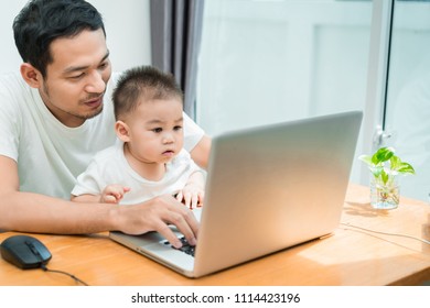 Asian Father And Little Son Typing Someting On Laptop Computer On Workplace At Office Home Happiness Laughing Together, Happy Family Concept.