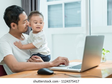 Asian Father And Little Son Typing Someting On Laptop Computer On Workplace At Office Home Happiness Laughing Together, Happy Family Concept.