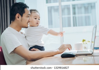 Asian Father And Little Son Typing Something On Laptop Computer On Workplace At Office Home Happiness Laughing Together, Happy Family Concept.