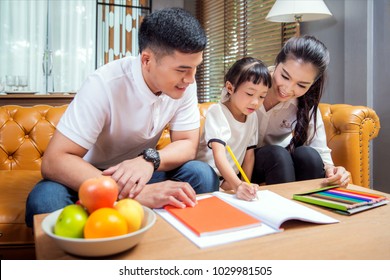 Asian father, mother and daughter doing home work togather in living room, this immage can use for education, home and family concept