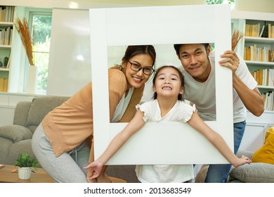 Asian Father ,mother And His Daughter Take Photo With White Frame For Keep Good Memory At Home.Activity Family Do Together.Lifestyle Drawing With Parent.