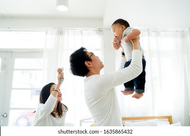Asian father and mother as married couple lifts their own son up and flies up in the air with laughter and happiness. He is raised up with excitement. Parenthood in Asia concept