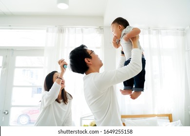 Asian father and mother as married couple lifts their own son up and flies up in the air with laughter and happiness. He is raised up with excitement. Parenthood in Asia concept