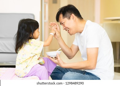 Asian Father Is Playing With His Daughter During Breakfast Time In The Hospital And His Daughter Feeling Better From Her Illness, Concept Of Care And Support Of Parent In Family Lifestyle.