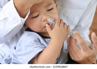  Asian father rinsing  baby's stuffy nose using a syringe of saline water - effective  remedy for clearing a baby's clogged nose - Shutterstock ID 2159818847