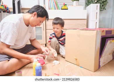 Asian father and son enjoy using paintbrush painting on cardboard box at home, Fun art and crafts for little kids, Children's Art Project, DIY Toys from Recyclable Materials,  Home schooling concept