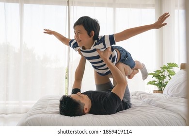 Asian Father And Son Have Good Time Playing Together On Bed At Home. Concept Of Dad And Son Relationship And Father Day