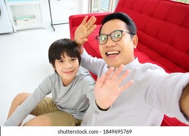 Asian father and son waving hand to camera for video call for online and internet communication concept - Powered by Shutterstock