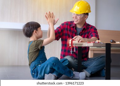 Asian Father Teaching Kid Son To Use Tools. Son Helping Dad With Building Work And Giving High Five At Their Home