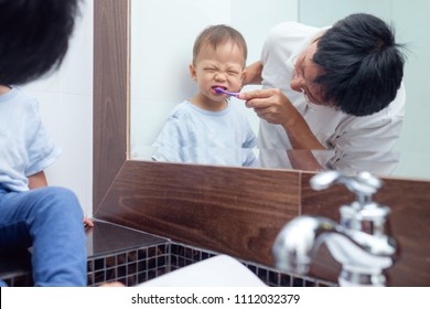 Asian Father Teaching Kid Teeth Brushing, Cute Little 18 Months / 1 Year Old Toddler Boy Child Brushing Teeth & Look In Mirror With Dad In Bathroom, Tooth Care For Children, Child Development Concept