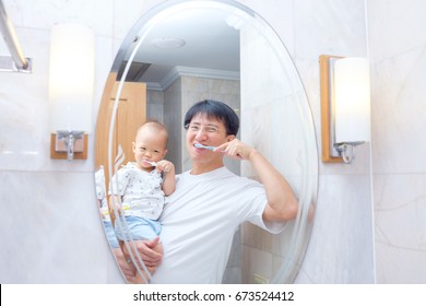 Asian Father Teaching Kid Teeth Brushing, Cute Little Asian 18 Months / 1 Year Old Baby Boy Child Brushing Teeth And Look In The Mirror With Dad In Bathroom, Child Development Concept With Copy Space