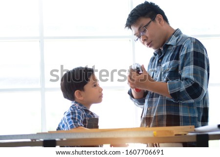 Asian father teaching son how to use tools at workshop, father and son concept