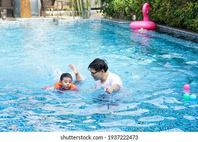 Asian Father Teaching Son To Swim At Swimming Pool. Family Outdoor Activity On Holiday In Summer Weather