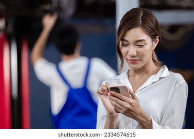 Asian feamale customer talking mobile phone standing at service auto repair shop. Woman talking on phone with car repair and agreeing repair cost with insurance. - Powered by Shutterstock