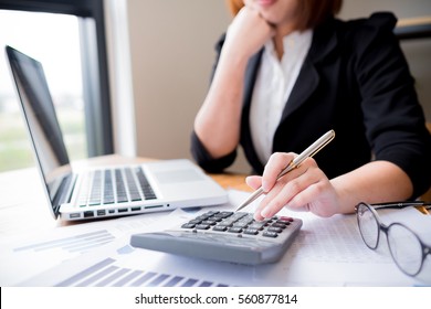 Asian female accountant or banker making calculations. Savings, finances and economy concept through a laptop.