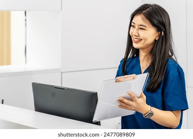 Asian female administrator talks with patient. Adult woman stands near reception desk in clinic lobby area, asks information, makes appointment with doctor. Medical staff work in modern hospital. - Powered by Shutterstock