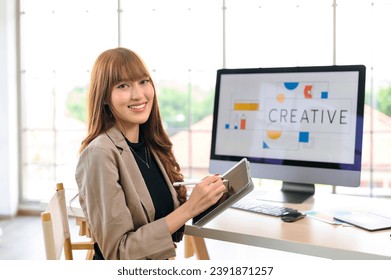 Asian female artist drawing something on graphic tablet. graphic designer working at office. Looking at camera - Powered by Shutterstock