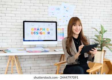 Asian female artist drawing something on graphic tablet. graphic designer working at office. Looking at camera - Powered by Shutterstock