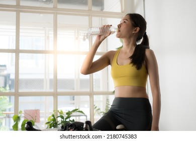 Asian Female Athletes Take A Break To Drink Water While Doing Cycling Exercises In Their Free Time From Working At Home.