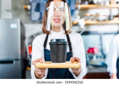 Asian Female Barista Serving Coffee To Customer In Black Take Away Coffee Cup, Wearing Clear Face Shield, New Normal Coffee Shop Concept, Selective Focus