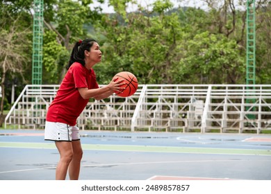 Asian female basketball player holding ball ready to shoot in court - Powered by Shutterstock
