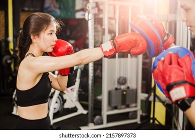 Asian Female Boxer Training Punch The Trainer's Aim.