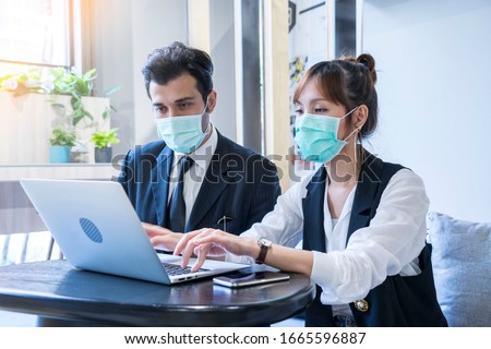 Asian female and Businessman workers meeting together with laptop and wear protective masks prevent PM 2.5 and corona virus or covid19 at co working space .Health and teamwork concept