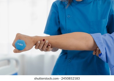 Asian female caregiver helps a satisfied elderly man exercise with dumbbells at home. Elderly treatment center high level medical care - Powered by Shutterstock