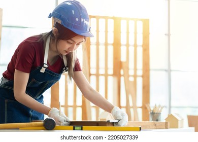 Asian Female Carpenter Working With Machinist Square To Measure Of Wood In The Wood Workshop