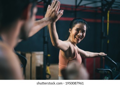 Asian Female And Caucasian Male Athletes Or Sport People Giving High Five Together After Successed Training On Stationary Bicycle. Health Care And Fitness In Gym Concept