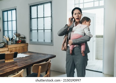 Asian Female Ceo Carrying Toddler Just Getting Home Is Receiving Emergent Phone Call From Company. Chinese Businesswoman With Baby Opening Mouth Wide Is Surprised At A Bad News She Hears On Phone.