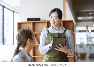 Asian female clerk taking orders at a cafe - Powered by Shutterstock