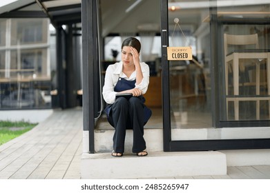 Asian female coffee shop owner Stressed barista Headache and regret hanging the shop closed sign on the entrance. I feel sad that I had to close my business. business shut down startup business idea. - Powered by Shutterstock