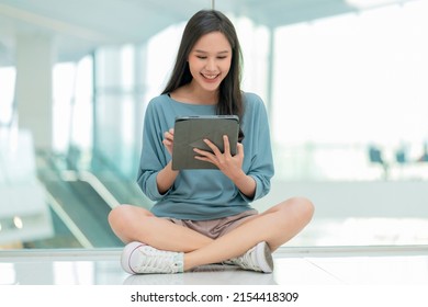 asian female collage young campus woman sitting on the mall floor using tablet browing surf data online social media with cheerful fun smiling,asian woman digital nomad sit on floor casual work online - Powered by Shutterstock