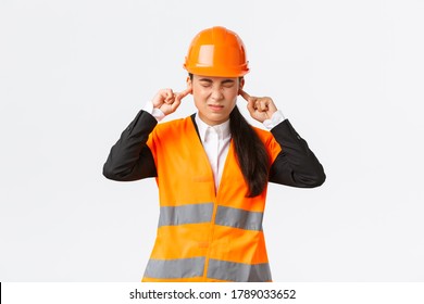 Asian Female Company Manager Feeling Discomfort, Chief Engineer Shut Ears And Grimacing From Annoying Noise, Inspect Work At Construction Zone, Awful Sound Of Repairment, Wear Safety Helmet