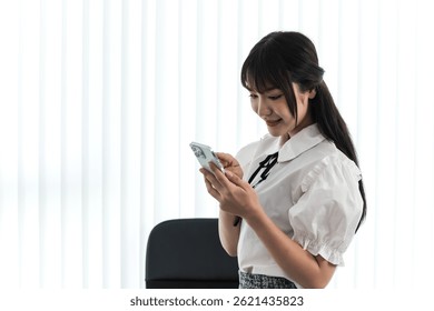Asian female content creator looking at smartphone feeling happy with successful increasing subscribers and  followers