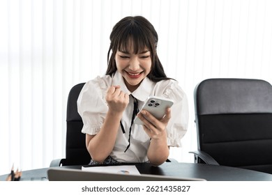 Asian female content creator looking at smartphone feeling happy with successful increasing subscribers and  followers