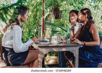 Asian Female Coworkers At Meeting Discuss Their Project Sitting At Table Outside And Using A Laptop With Tablet In Daytime.