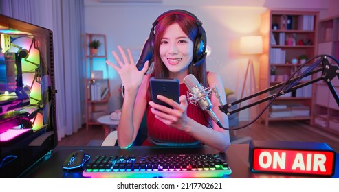asian female cybersport gamer have live stream with on air light sign and playing mobile game by the smartphone at home