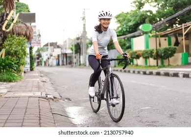 Asian Female Cyclist In Sport Clothing And Helmet