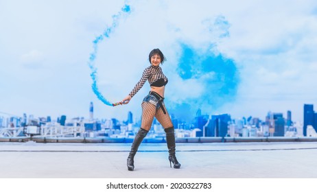 asian female dancer showing contemporary and modern dance performance with blue color smoke on rooftop of highrise building in urban - Powered by Shutterstock