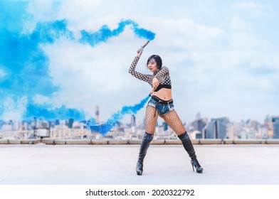 asian female dancer showing contemporary and modern dance performance with blue color smoke on rooftop of highrise building in urban - Powered by Shutterstock