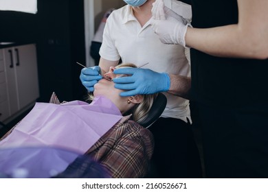 Asian Female Dentist Doctor In PPE Wearing Protective Facemask And Shield During Coronavirus Pandemic Examining Tooth For Young Girl Patient On Dental Chair For Oral Care Treatment Procedure At Clinic