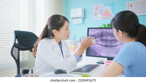 Asian Female Dentist Showing Teeth Xray At Dental Clinic - She Explains To Patient With Teeth Whitening Tool