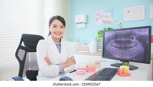 Asian Female Dentist Works At Dental Clinic Showing Teeth Xray - She Looks At Camera Smily With Crossed Arms