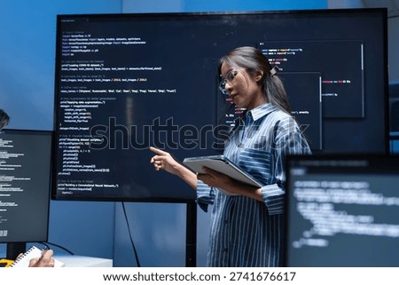 Asian Female Developer Presenting code on the screen, talking and discussing with team while working late in tech office at night. Two Software developer meeting in office to planning new project.