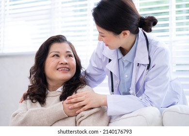 Asian Female Doctor Examining An Elderly Woman At Home