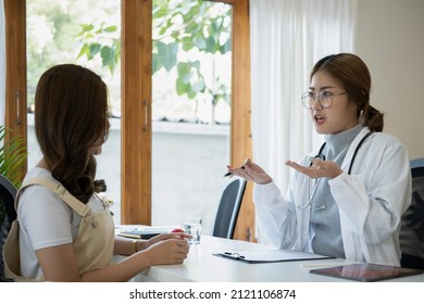 Asian Female Doctor Explaining Diagnosis To Her Patient.